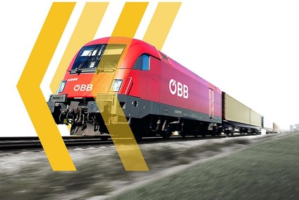 Rote ÖBB-Lokomotive zieht einen Containerzug auf offener Strecke, mit grafischen gelben Pfeilelementen im Vordergrund