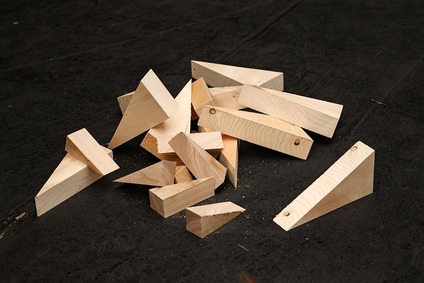 Assorted wooden blocking pieces and wedges used for cargo securing on an industrial floor.