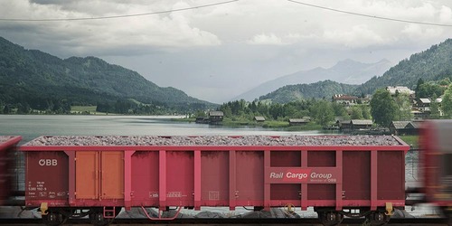 Rendering eines roten ÖBB Rail Cargo Group Güterwagens vor alpiner Seelandschaft
