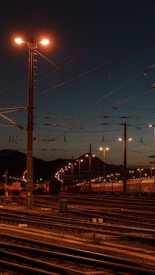 Güterwagen in einem beleuchteten Rangierbahnhof in der Dämmerung
