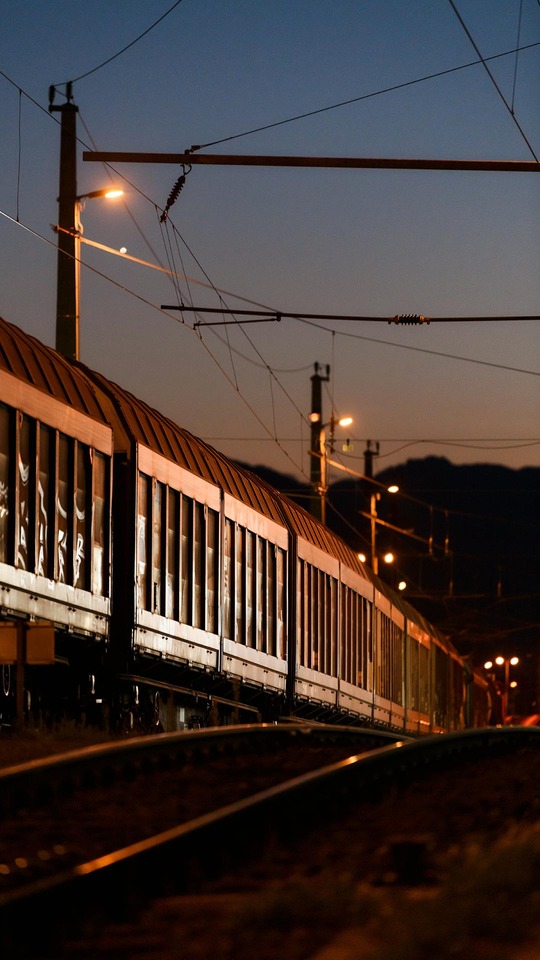 Freight train at dusk with illuminated rail infrastructure