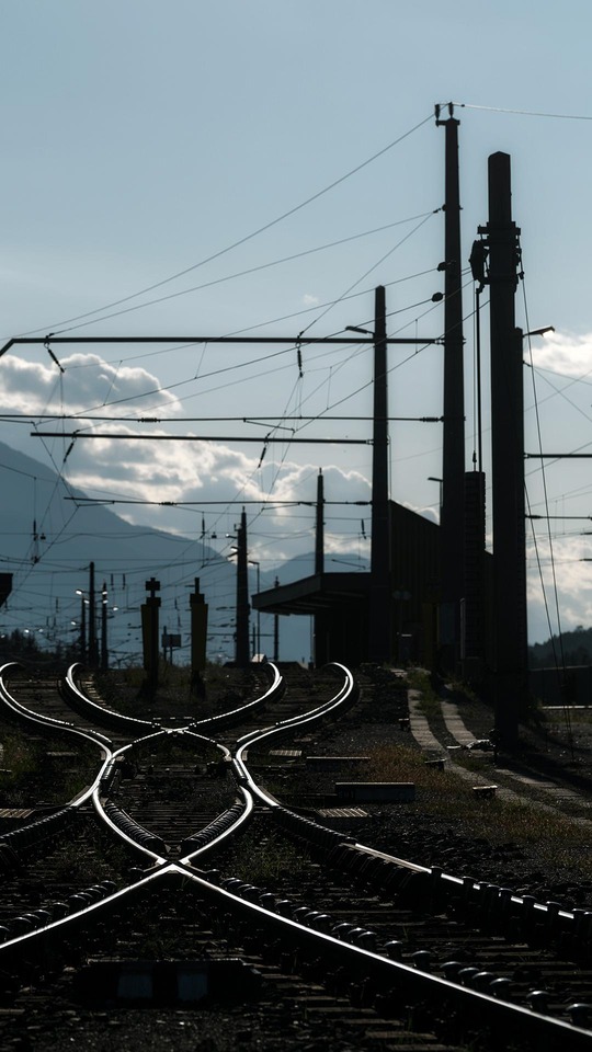 Gleisanlage mit Oberleitungen an einer Weiche nahe einem Bahnhof