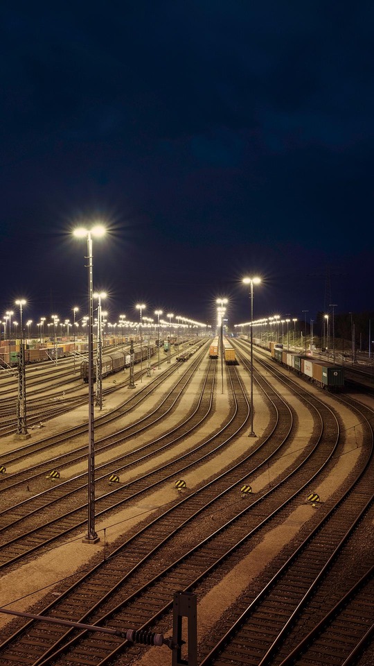 Illuminated railway yard with multiple tracks and freight wagons at night