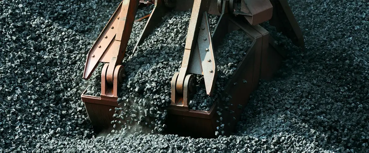 Greifer entlädt Schotter auf einer Baustelle im Gleisbereich