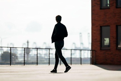 Person geht auf einer Terrasse mit Stadthafen im Hintergrund
