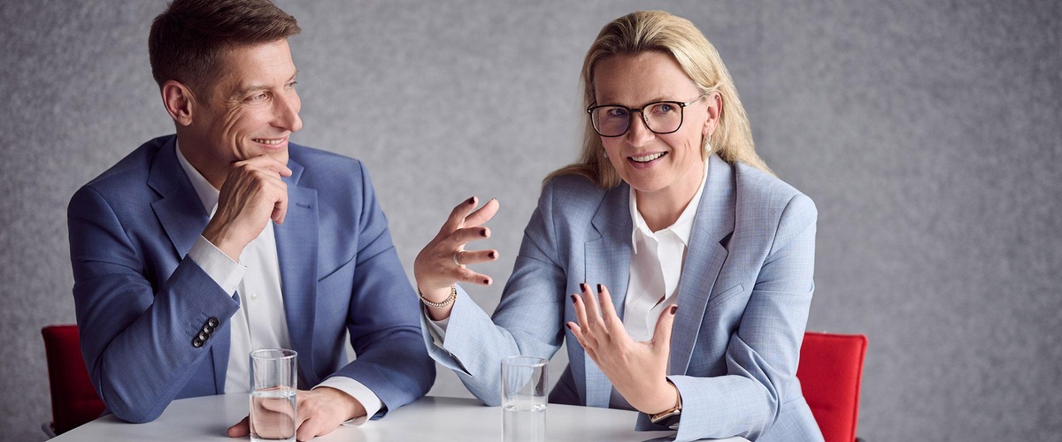 Christoph Grasl und Bettina Castillo an einem Besprechungstisch diskutierend