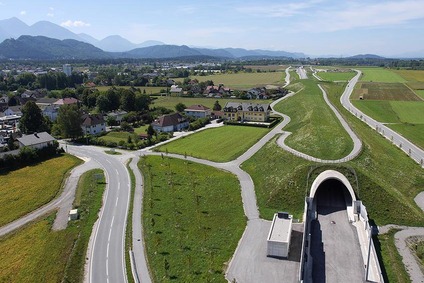 Luftaufnahme einer ländlichen Ortschaft mit Straßen, Feldern und Tunneleinfahrt
