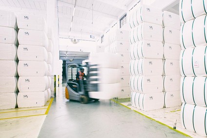 Gabelstapler transportiert Ladung zwischen großen weißen Ballen im Lager