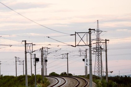 Electrified rail line bending through open landscape under evening sky