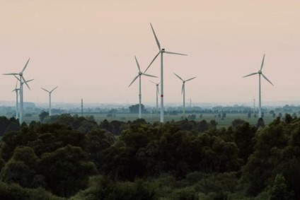 Windräder über einer bewaldeten Landschaft bei Sonnenuntergang