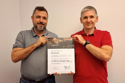 Zwei Männer halten eine Nachhaltigkeits-Auszeichnung für Danucem