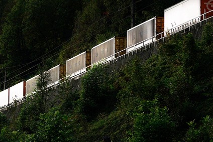 Containertransport per Güterzug auf einer Bahnstrecke in bewaldeter Landschaft