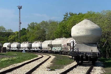 Mehrere Kesselwagen eines Güterzugs auf einer kurvigen Bahnstrecke in ländlicher Umgebung