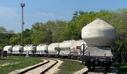 Güterzug mit Kesselwagen fährt durch eine Kurve auf einer Bahnstrecke im Grünen