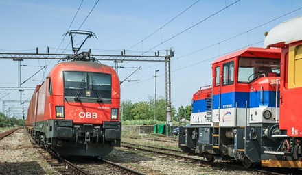 Rote ÖBB-Lokomotive auf einem Gleis neben einer Rangierlok in einem Bahnbetriebsbereich