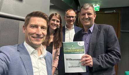 Vier Vertreterinnen und Vertreter der Rail Cargo Group beim IBS Congress mit Schild „Willkommen / welcome“