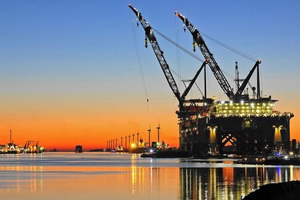 Großes Kranschiff im Hafen von Rotterdam bei Sonnenuntergang, Windräder im Hintergrund