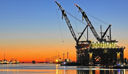 Hafen Rotterdam bei Sonnenuntergang mit großem Kranschiff und Windrädern im Hintergrund