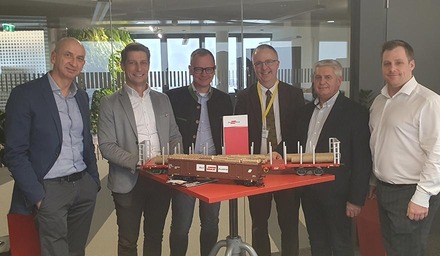 Führungskräfte der Rail Cargo Group mit Partner Papierholz Austria vor Modell eines Holztransportwagens