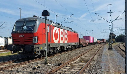 ÖBB Güterzug mit Containerwagen fährt durch Bahnhofsgleis