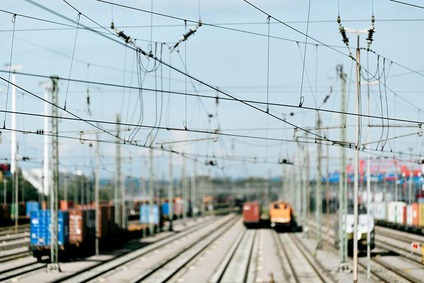 Rangierbahnhof mit mehreren Gleisen, Güterwagen und Oberleitungen im Hintergrund