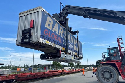 Container wird mit einem Reachstacker auf einen Bahnwagen verladen