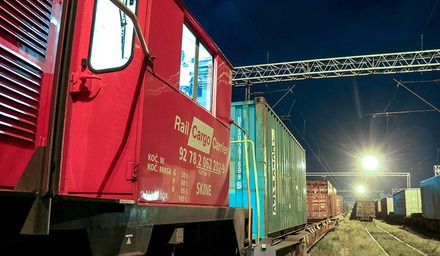 Lokomotive von Rail Cargo Carrier zieht einen Containerzug in einem Güterbahnhof bei Nacht