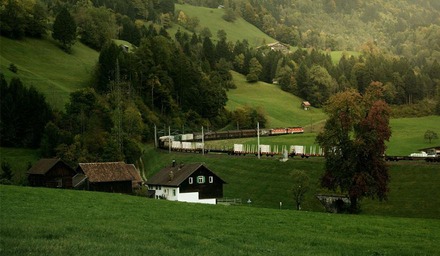ÖBB Güterzug der Rail Cargo Group fährt durch eine grüne Hügellandschaft mit Wald und Wiesen