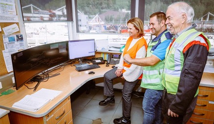 Mitarbeitende mit Sicherheitswesten stehen vor mehreren Monitoren in einer Leitstelle