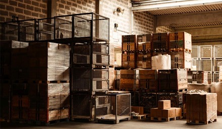 Lagerbereich mit gestapelten Transportkisten, Paletten und Gitterboxen
