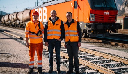 Drei Mitarbeitende der ÖBB Rail Cargo Group vor einem Güterzug mit ÖBB-Lokomotive
