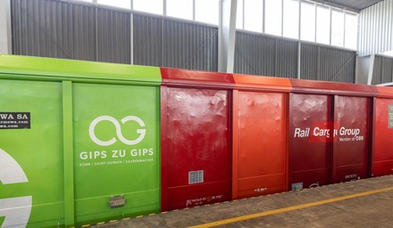 Mehrfarbiger Güterwagen mit Rail Cargo Group Logo und „Gips zu Gips“ Schriftzug in einer Lagerhalle