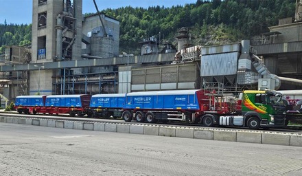 MOBILER-Behälter auf Lkw und Güterzug vor einer Industrieanlage