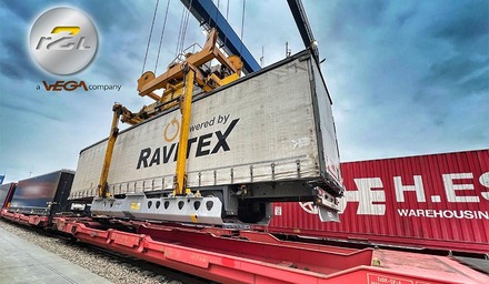 Kran hebt einen Wechselaufbau auf einen Güterwagen im Terminal
