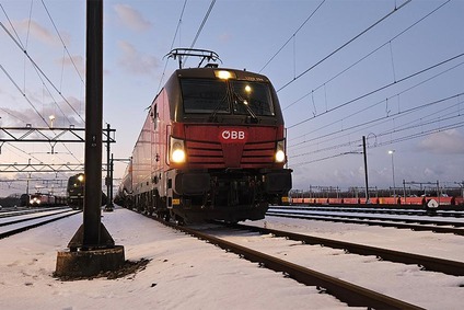 Rote ÖBB Vectron-Elektrolok im verschneiten Rangierbahnhof bei Dämmerung, mit Scheinwerfern.