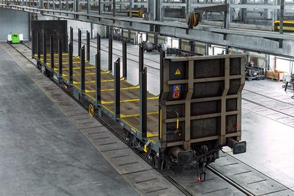 Leerer Rundholzwagen für den Holztransport in einer Werkshalle, mit senkrechten Rungen für Stammholz.