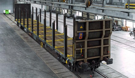 Leerer Rundholzwagen für den Holztransport in einer Werkshalle, mit senkrechten Rungen für Stammholz.
