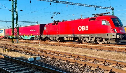 Rote ÖBB-Lokomotive mit Rail Cargo Group Güterwagen auf Gleisen