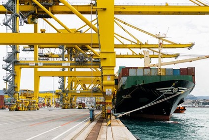 Containerschiff im Hafen unter gelben Portalkränen beim Be- und Entladen von Frachtcontainern