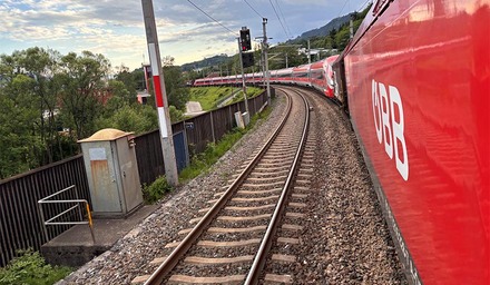ÖBB Zug fährt durch grüne Berglandschaft auf kurviger Strecke