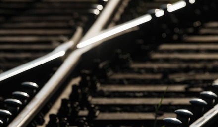 Nahaufnahme von Eisenbahnschienen an einer Weiche mit kreuzenden Gleisen im unscharfen Hintergrund