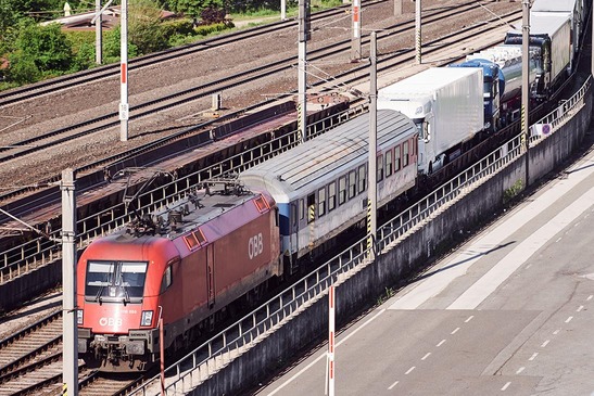 Rolling highway transporting trucks by rail on low-floor wagons along railway corridor