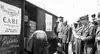 Historisches Bild: CARE Pakete werden aus Waggon ausgeladen, Soldaten schauen zu