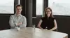 Die Praktikant:innen Laura und Konstantin bei einem Gespräch im Büro mit Blick auf die Stadt.