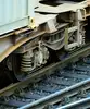 Nahaufnahme eines Güterwagen-Drehgestells mit Rädern und Federung auf Eisenbahnschienen