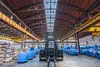 Warehouse Desio with forklift in the center and stacked blue steel coils under a tall hall structure