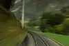 Blurred railway tracks in a curve, seen from a moving train.