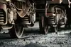 Close-up of freight wagon wheels on gravel.