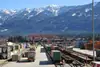 Containerterminal Villach Süd mit gestapelten Containern, Güterwagen und Portalkran vor alpiner Bergkulisse