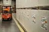 Forklift moving pallets with paper rolls.